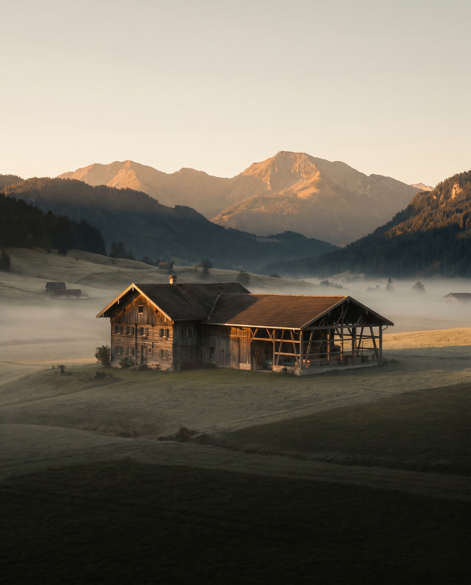 Sonnenaufgang über einem Holzhaus mit Werkstatt, Felder und Berge im Hintergrund